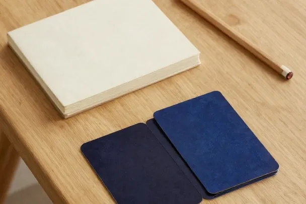 Baraja de reverso liso junto a un cuaderno cerrado y un lápiz