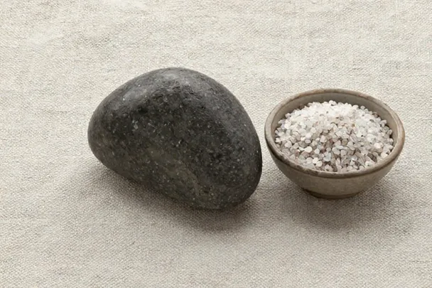 Piedra oscura junto a un cuenco de sal gruesa.
