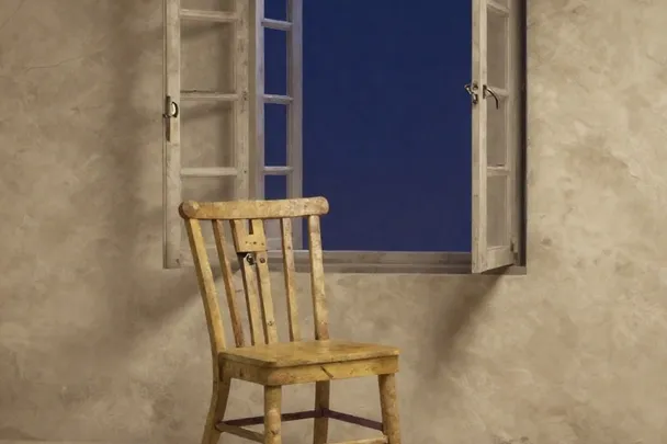 Silla vacía mira hacia una ventana parcialmente abierta