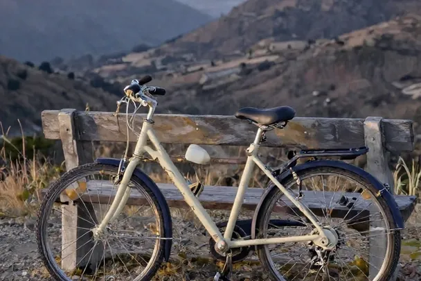 Bicicleta sin marcas reposa junto a un banco frente a un paisaje abierto