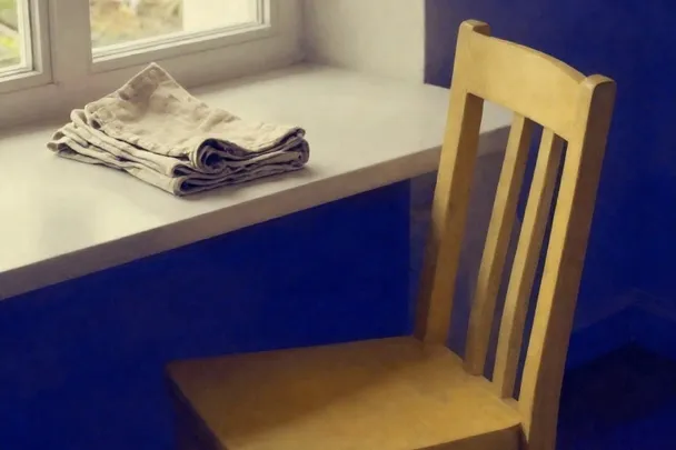 Sillón de madera vacío junto a una mesa de trabajo despejada.