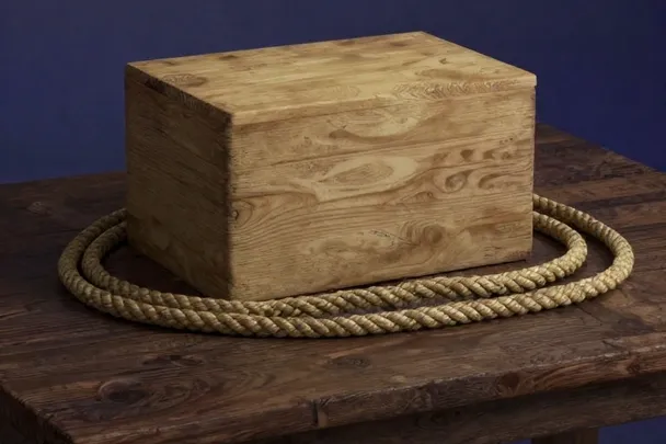 Caja de madera cerrada rodeada por una cuerda suelta.