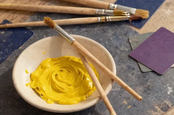 Pinceles sin marca y pigmento amarillo iluminan un estudio sencillo