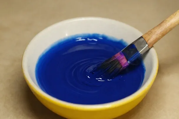 Pigmento azul se mezcla suavemente con agua en un cuenco de cerámica