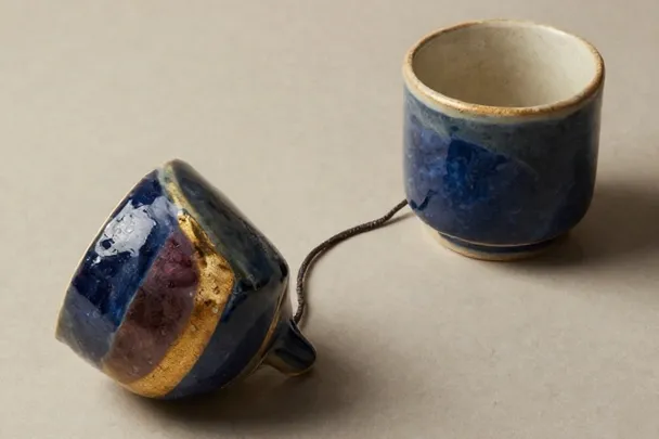 Two empty speaking cups are connected by a loose thread with a slack loop.