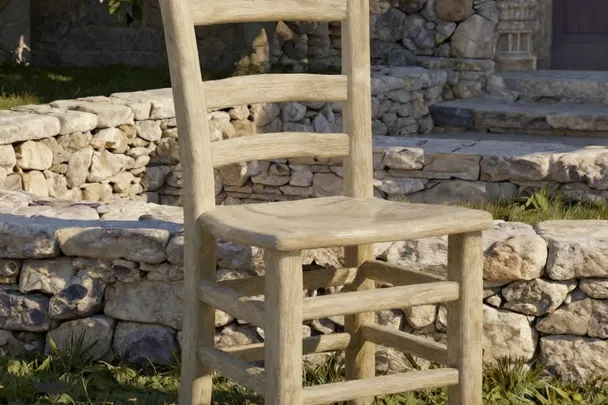 A sturdy empty chair stands beside a low stone boundary in a peaceful courtyard.