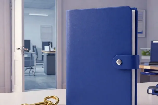 A closed indigo portfolio and simple brass key beside a quiet office doorway