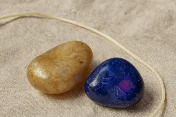 Two distinct smooth stones rest close together beside a gently curving thread.