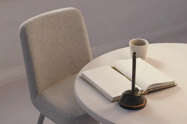 An empty reading chair beside a plain table and closed notebook