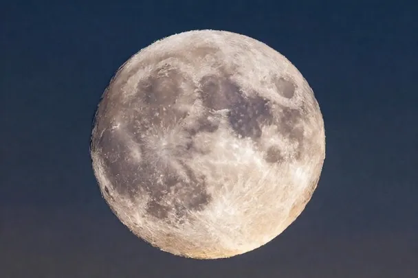 Luna parcialmente iluminada sobre un paisaje tranquilo al anochecer