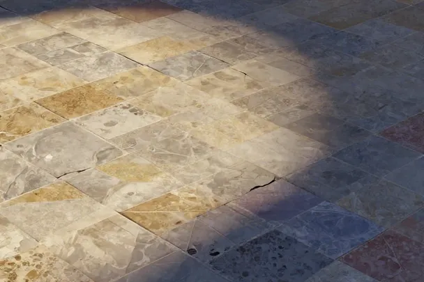 Baldosas desplazadas sobre un suelo de piedra en calma.