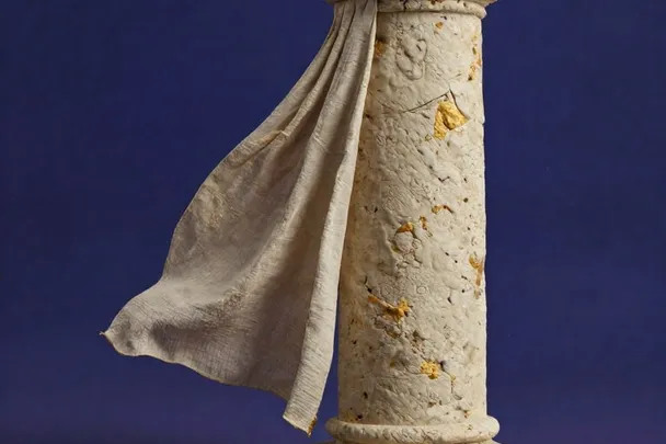Columna de piedra lisa se mantiene firme ante una cortina movida por la brisa