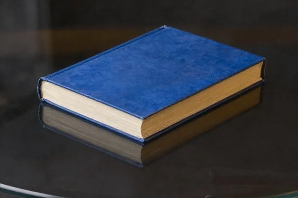 Libro cerrado se refleja invertido en una superficie de vidrio limpia