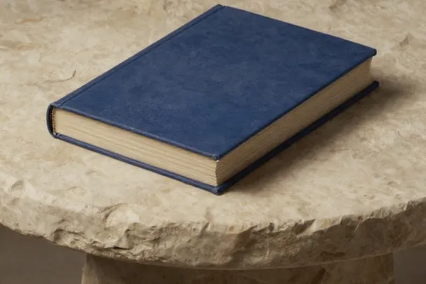 Libro cerrado de cubierta azul descansa sobre una mesa de piedra robusta