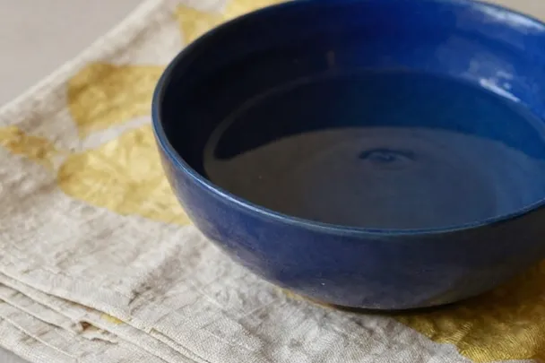 Agua clara llena un cuenco azul sobre lino bien doblado