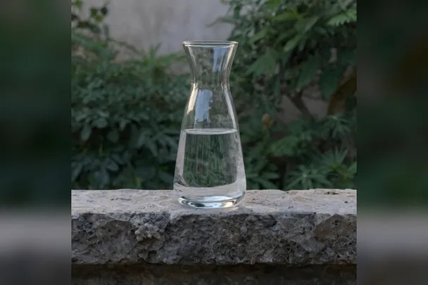 Jarra de cristal con agua sobre un alféizar de piedra.