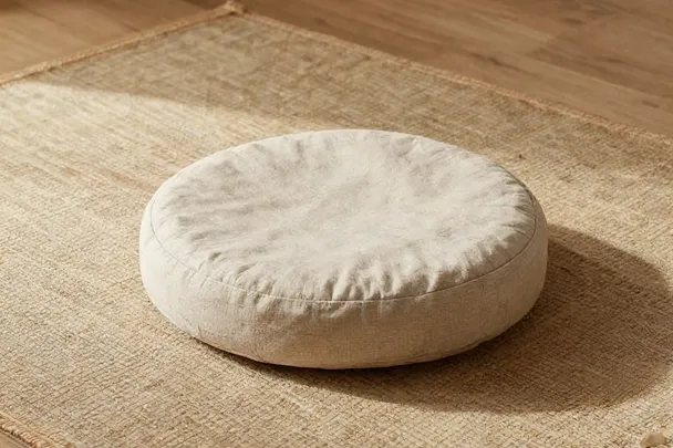 Cojín de meditación sobre una esterilla de fibras naturales.