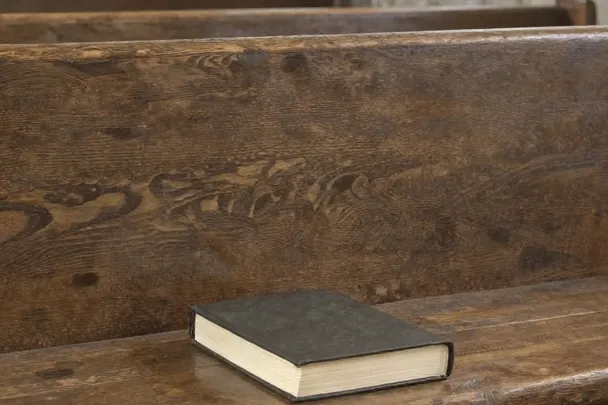 Banco de capilla con un pequeño libro de oración cerrado.