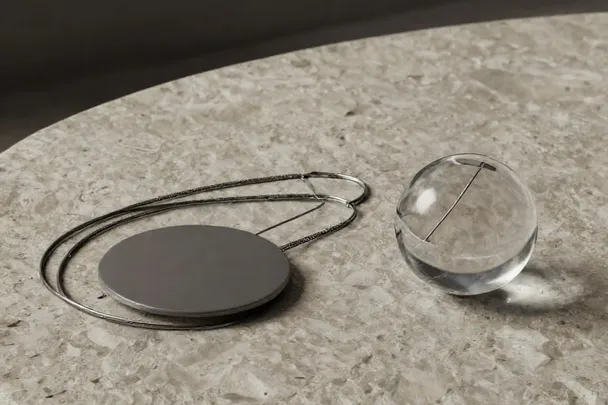 Péndulo y esfera de cristal reposan separados sobre una mesa lisa