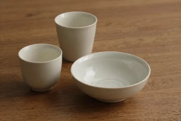 Copas de cerámica junto a un cuenco de agua sobre una mesa.