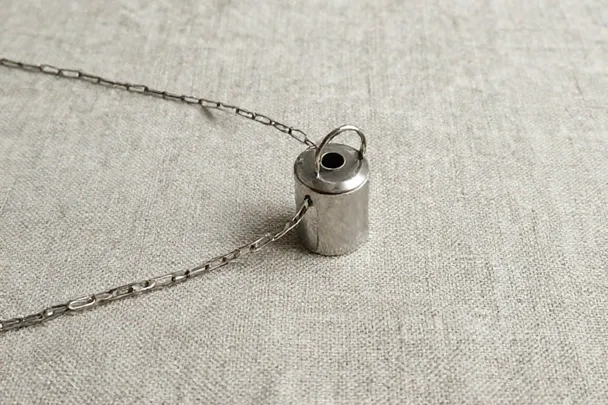 Péndulo de metal unido a una cadena sobre lino.