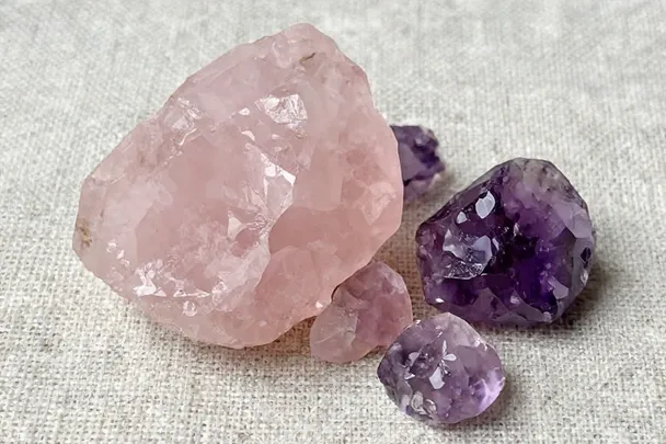 Piezas rugosas de cuarzo rosa y amatista sobre lino.