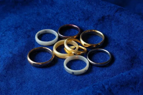 Anillos lisos reposan sobre pliegues de lino azul