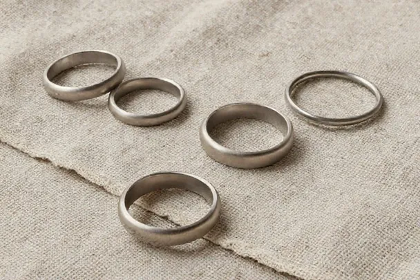 Varios anillos lisos reposan sobre lino natural