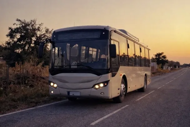 Autobús sin marcas espera en una carretera tranquila al amanecer