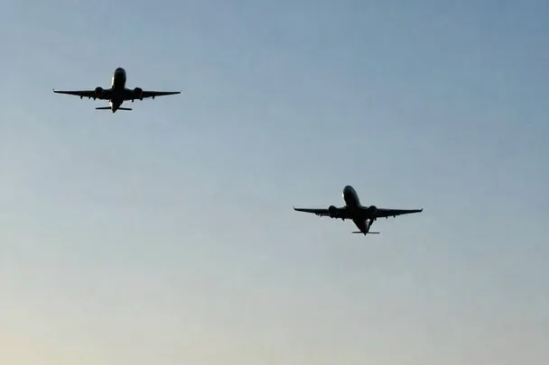 Dos aviones sin marcas vuelan separados bajo un cielo claro