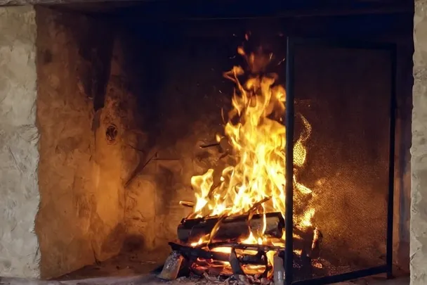 Fuego pequeño arde contenido dentro de un hogar de piedra seguro
