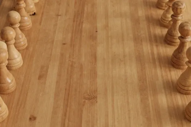 Filas opuestas de piezas de madera esperan sobre un tablero liso