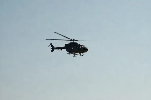 Helicóptero sin marcas cruza un cielo amplio sobre colinas tranquilas