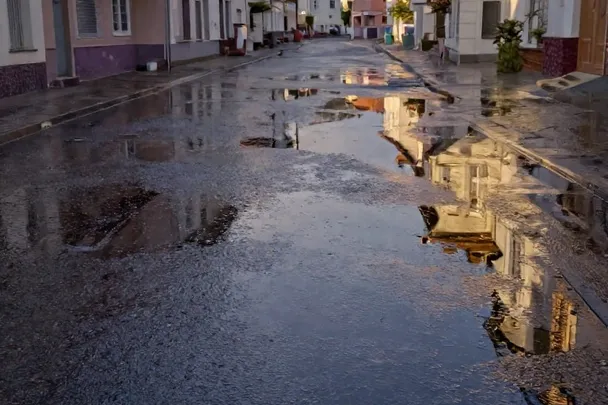 Calle vacía cubierta por agua tranquila refleja las fachadas al amanecer