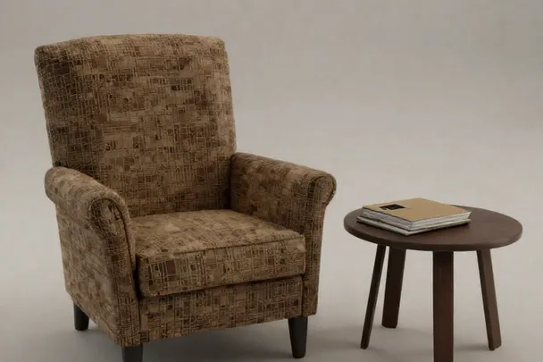 Sillón vacío junto a una mesa auxiliar con un pequeño álbum cerrado.