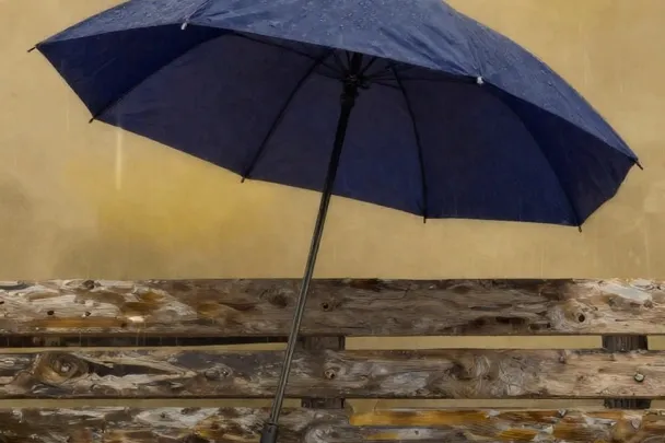 Paraguas índigo abierto protege un banco vacío bajo la lluvia