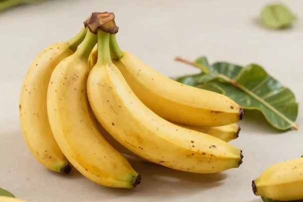 Plátanos maduros descansan con hojas sobre una mesa clara