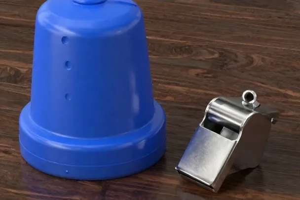 Baliza azul lisa y silbato metálico descansan sobre una mesa
