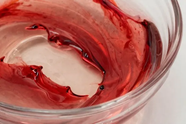 Tinte rojo natural forma una mancha limpia en un cuenco de vidrio
