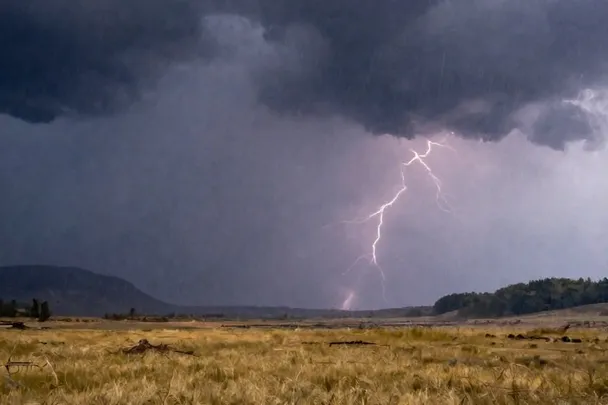 Tormenta lejana cruza un valle mientras el primer claro ilumina el campo