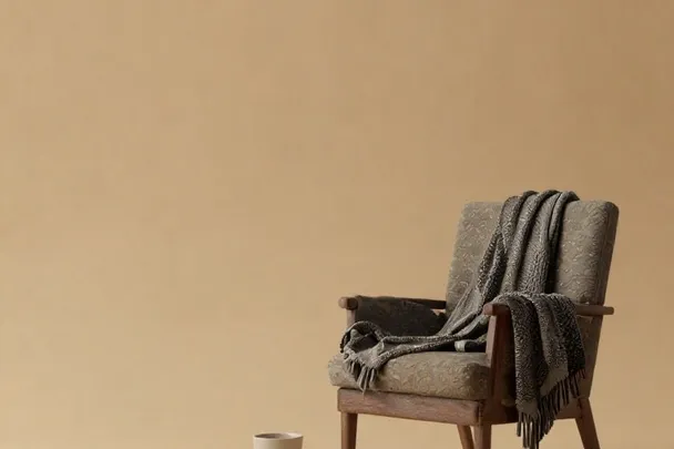 Sillón vacío con chal tejido permanece junto a una taza