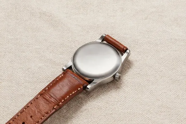 Reloj de pulsera con esfera lisa descansa sobre tela azul