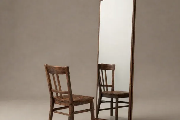 Silla vacía y su reflejo en un espejo de pared.