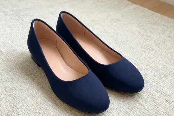 Par de zapatos azul oscuro sin marcas descansa sobre una alfombra clara
