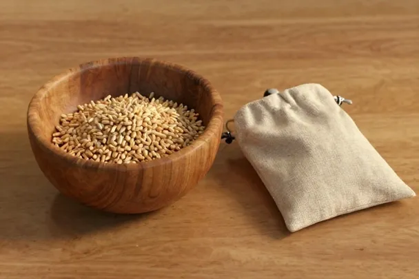 Cuenco de grano y bolsa de tela descansan sobre una mesa de madera