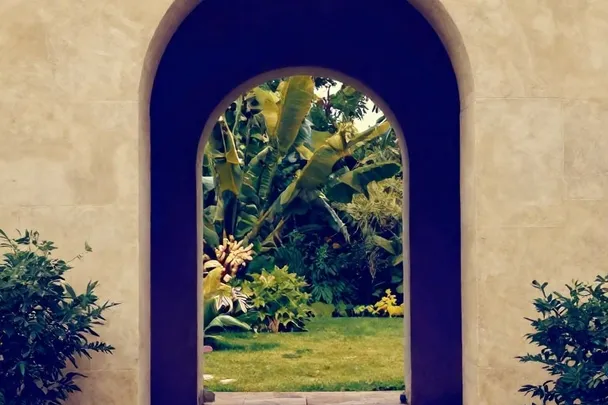 Arco de piedra equilibrado se abre hacia un jardín tranquilo