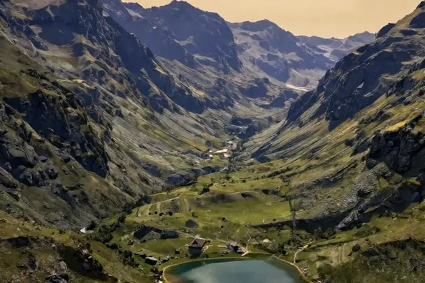 Valle de montaña verde rodea un lago bajo una luz suave