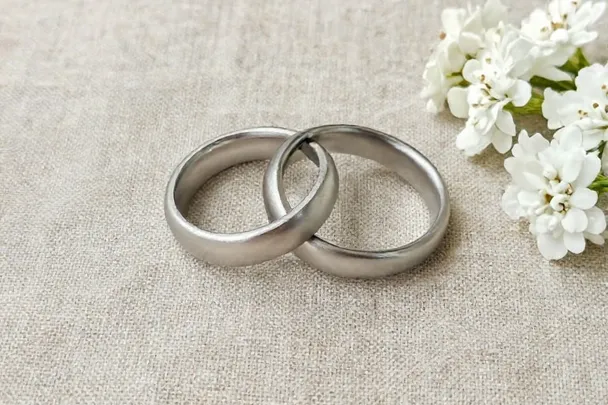 Dos anillos lisos reposan junto a flores blancas