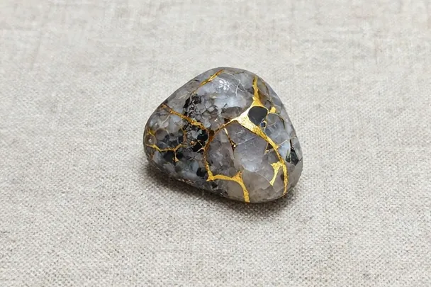 Piedra de cuarzo con vetas irregulares de oro nativo sobre lino claro.