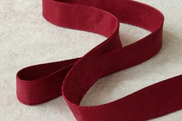 Cinta de tela roja doblada sobre lino claro.